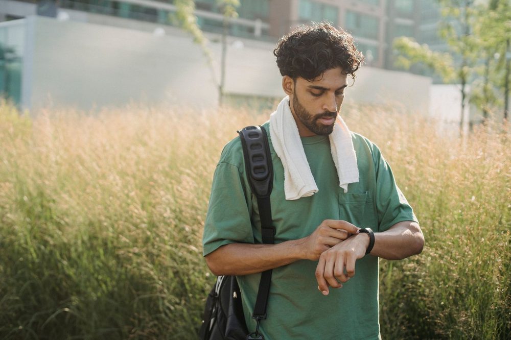 A man in a park checks his fitness watch after a morning workout, biohacking without the obsession