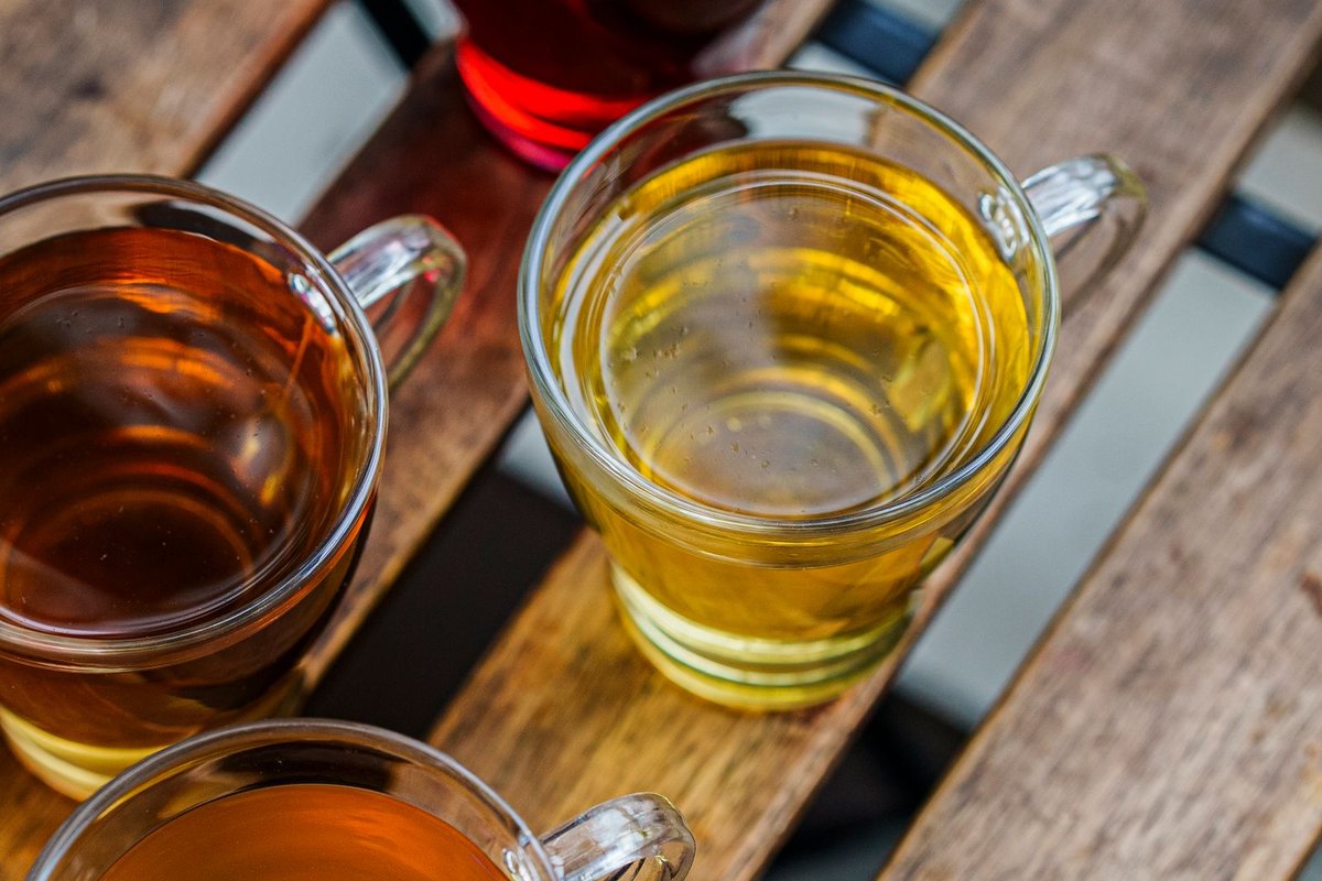 Ahşap bir masada üç fincan çay: yeşil, oolong ve siyah — çayda kafein