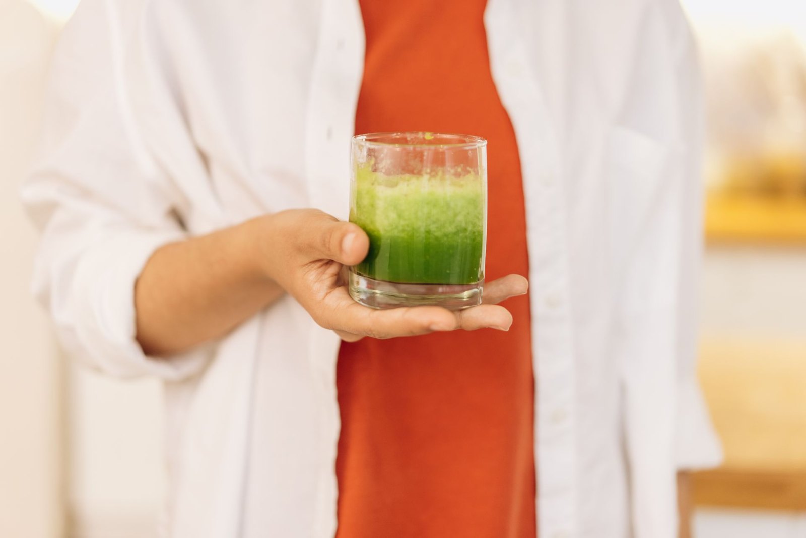 Segelas minuman hijau pagi di tangan — awal hari yang sehat