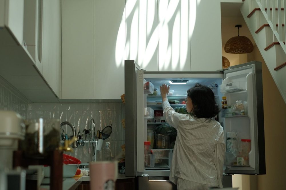 夜、開けた冷蔵庫の前で夕食を決められずに立つ人。1日の終わりの決断疲れ