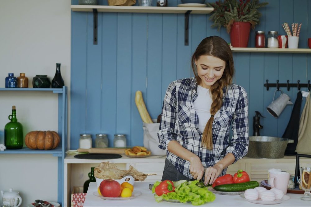Kobieta kroi świeże warzywa w jasnej kuchni – glutation w produktach i nawykach