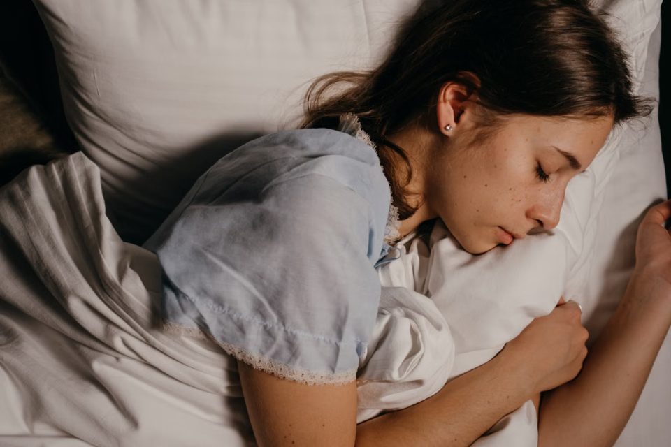 Une jeune femme dort profondément en serrant un oreiller : comment s'endormir rapidement et bien dormir