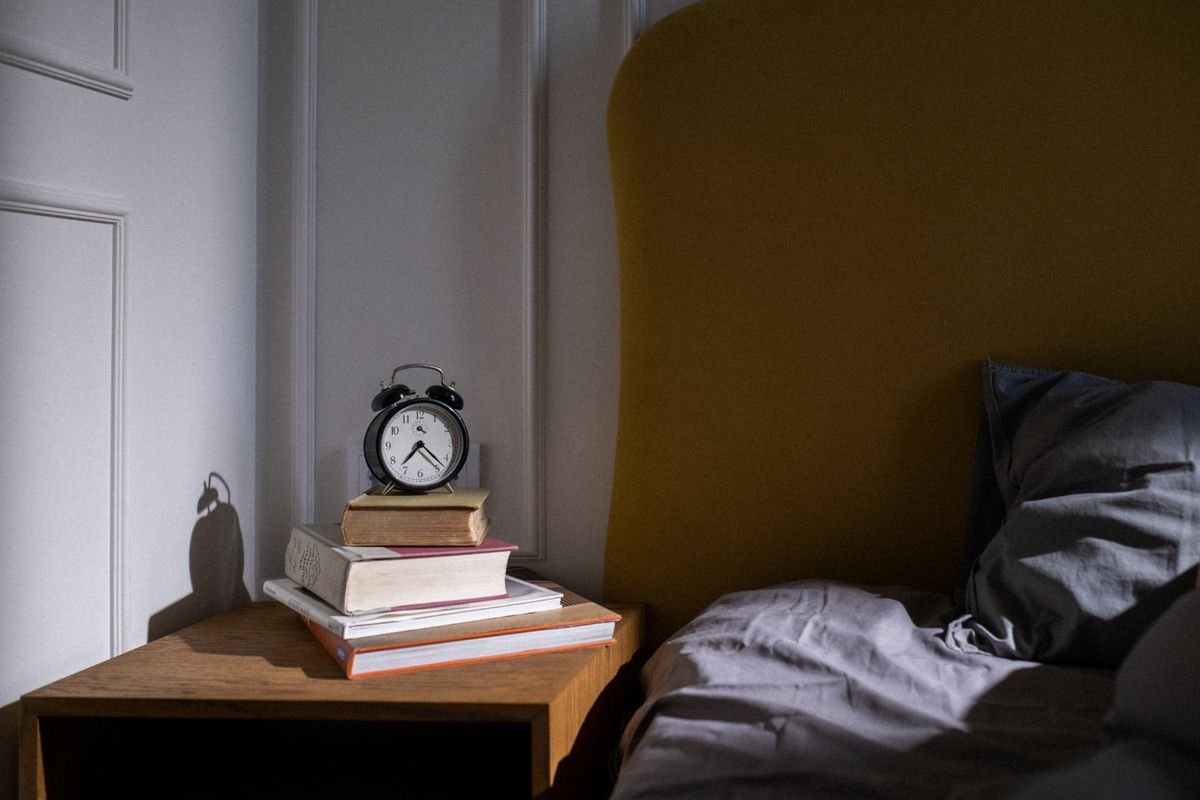 Despertador na mesa de cabeceira e luz noturna suave no quarto