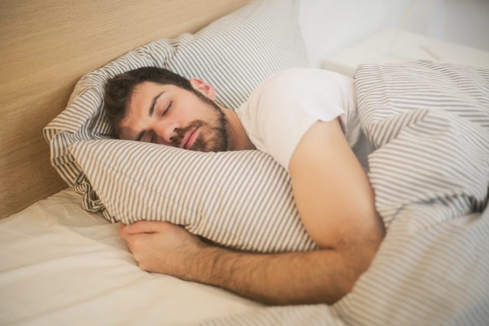 Mężczyzna śpi na boku, obejmując poduszkę – jak przestać chrapać