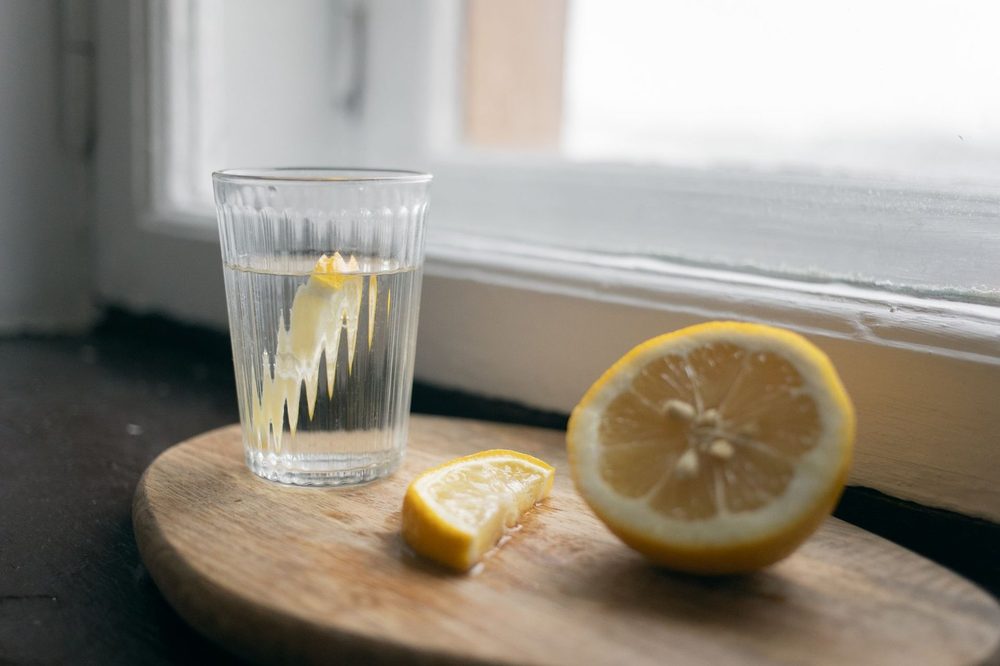 Segelas air dengan lemon di tingkap yang disinari matahari — air lemon waktu pagi dan mitos detoks