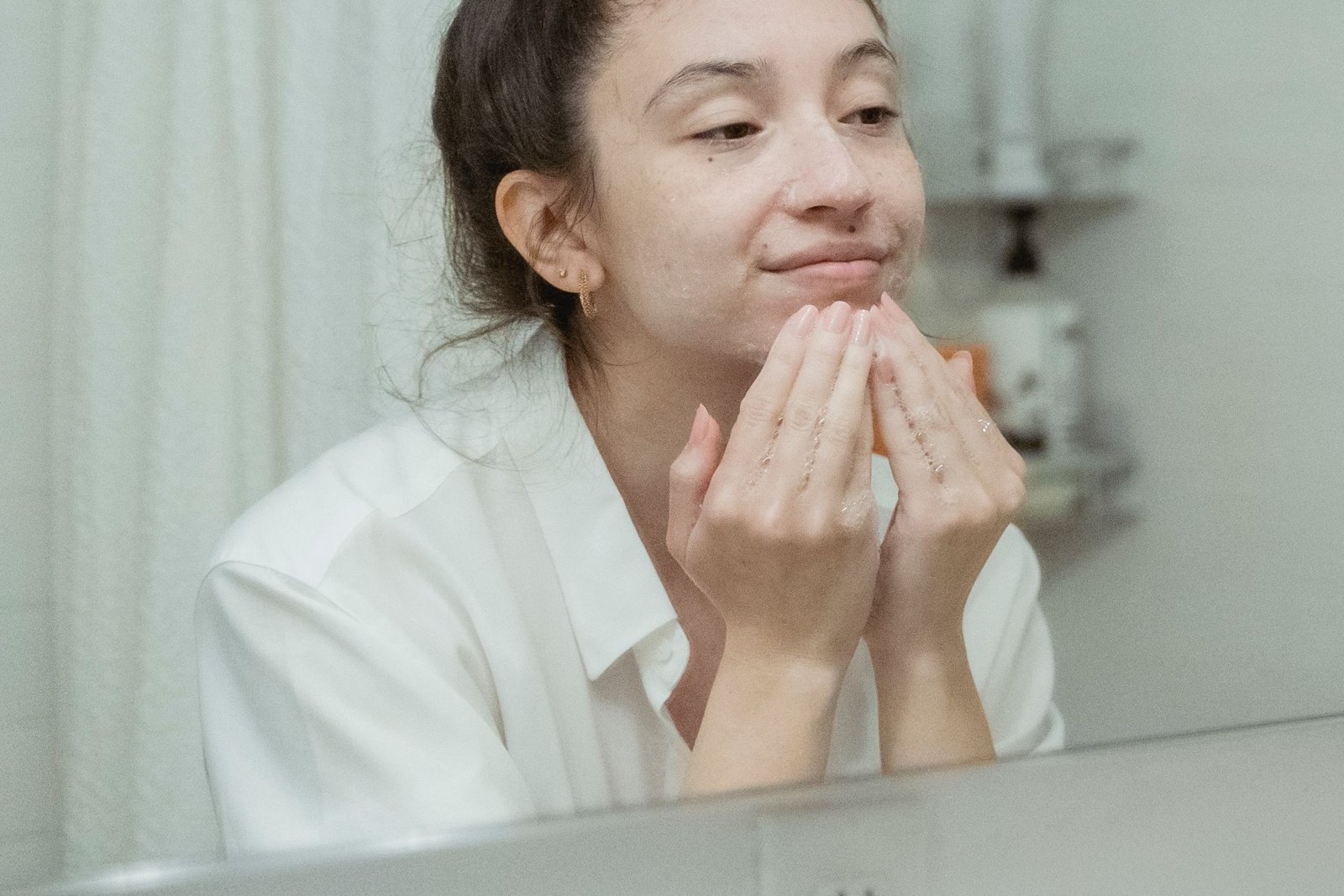 Wanita merawat kulit di depan cermin kamar mandi — ritual dengan patch Alavida