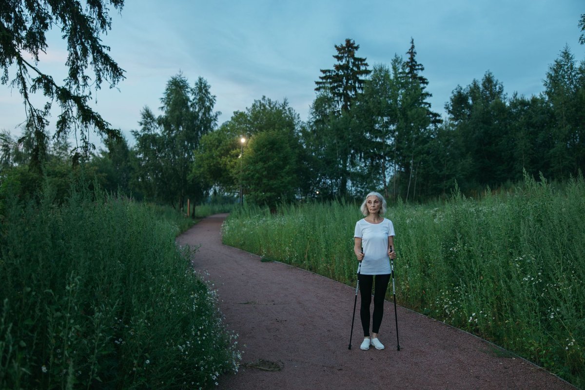 Orang-orang melakukan nordic walking dengan tongkat di taman pada musim gugur