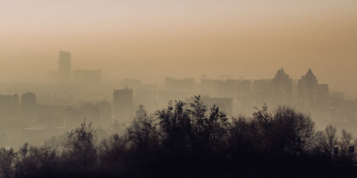 Cidade envolta numa neblina de smog de inverno com montanhas ao fundo: correr com poluição em Almaty