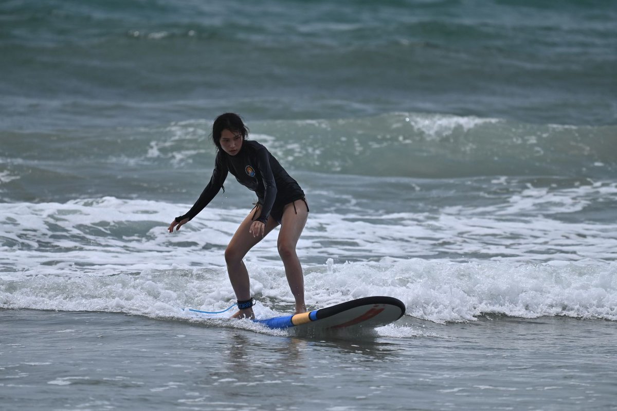 Beginner with a surfboard walking into ocean waves — surfing for beginners