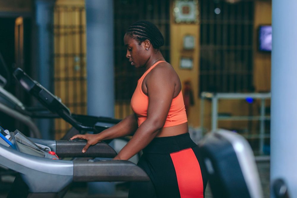 A woman walking on a treadmill, holding the handrails — a walking pad for walking while you work